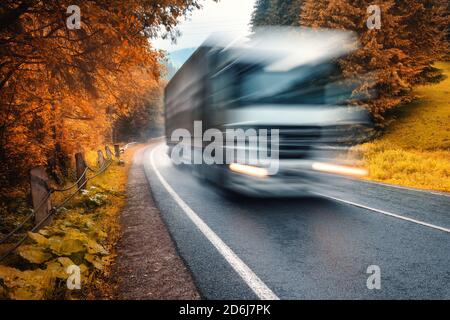 Verschwommener LKW auf der Straße im Herbst Nebelwald in Regentag Stockfoto