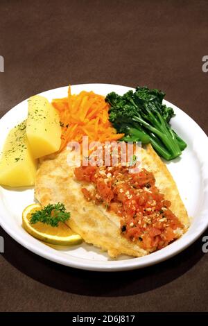 Gegrilltes Fischfilet mit gehackten Tomaten, Kartoffeln und Gemüse Stockfoto