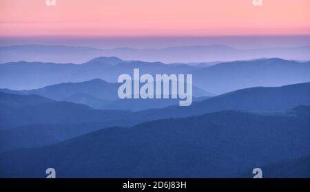 Bergrücken im Nebel bei Sonnenuntergang im Herbst. Wunderschöne Landschaft Stockfoto