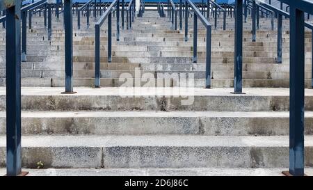 Externe mehrstufige Steintreppe. Es gibt viele Treppen und Geländer aus Metall. Viele Schritte in einer städtischen Umgebung, symbolisch abstrakt zurück Stockfoto