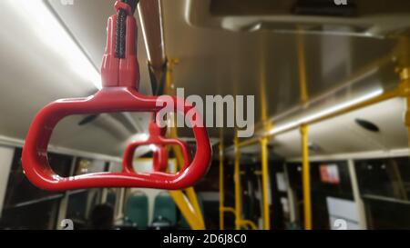 Roter Hängeländer an der Decke für stehende Passagiere im Transport. Moderne S-Bahn- und Stadtverkehr. Leerer Bus Stockfoto