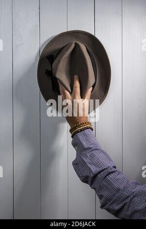 Ein alter Hut hängt an einer weißen Holzwand Stockfoto