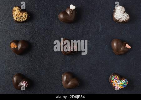 Schokoladenpralinen isoliert auf dunklem Hintergrund. Draufsicht, flach liegend. Stockfoto