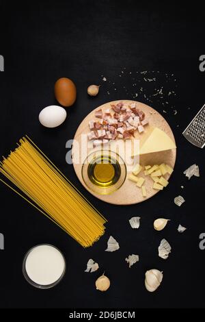 Traditionelle italienische Pasta Carbonara Zutaten: Speck, Spaghetti, Parmesan, Käse, Eier, Knoblauch, Sahne und Olivenöl. Draufsicht, flach liegend. Stockfoto