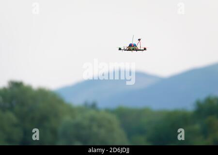 Kleine selbstgemachte FPV Racing Quad Copter Kamera Drohne fliegt vor den malvern Hügeln und Bäumen. Selektiver Fokus auf dieses autonome Flugzeug Stockfoto