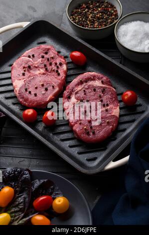 Kochen in einer Pfanne Rindfleisch Sirloin Steak gewürzt mit Pfefferkorn Und Salz auf schwarz Stockfoto