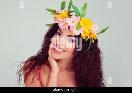 Schöne junge Frau lächelnd Modell mit Blumen auf dem Kopf floral Stirnband Frisur Make-up gelb rosa Lidschatten suchen glücklich lächelt Bei Camera isola Stockfoto