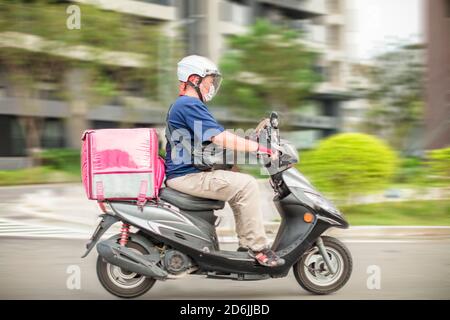 Mitarbeiter für die Lebensmittelzustellung fahren Motorräder, um Lebensmittel zu liefern Stockfoto