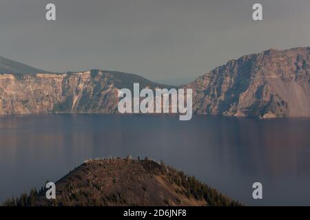 Blick über Wizard Island Cone zum Crater Lake und es ist Nordöstlicher Rand mit rauchgefüllter Luft von einem nahegelegenen Waldbrand Glühend am Nachmittag Sunshine Stockfoto