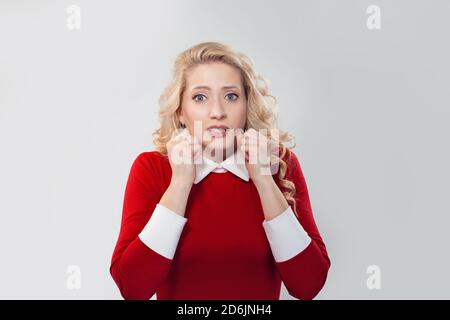 Vorfreude. Junge blonde Frau in rotem Kleid hält Fäuste in der Nähe Gesicht t in tiefen Schock und Angst Blick auf die Kamera. Kaukasische Geschäftsperson mit langem b Stockfoto