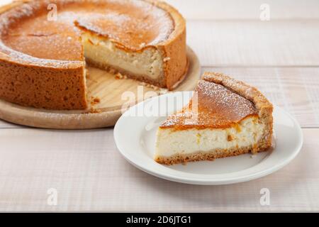 Hausgemachter Käsekuchen und ein Stück Kuchen in der Nähe auf dem Teller Stockfoto