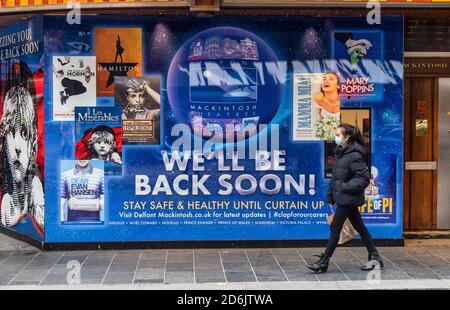 London, Großbritannien. Oktober 2020. Eine Frau mit Gesichtsmaske kommt an einer neuen Beschilderung vorbei mit ‘We'll be back soon' auf dem Sondheim Theater, das fertiggestellt wurde, nachdem Produzent Cameron Mackintosh angekündigt hatte, dass Les Miserables bis Weihnachten wieder in Londons West End kommen wird, mit Tickets, die bald nach Schließung erhältlich sind Nach Großbritannien, das die Sperre eingeht. Kredit: SOPA Images Limited/Alamy Live Nachrichten Stockfoto