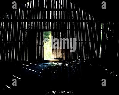 Licht, das durch Lücken in der Wand einer alten Scheune scheint. Stockfoto