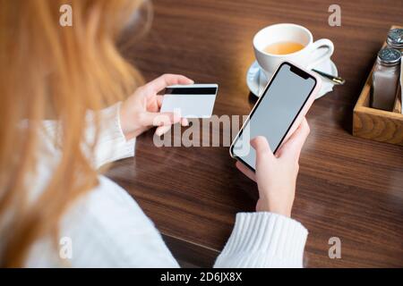 Nahaufnahme einer weiblichen Hand - Frau, die Kartenzahlung über das Mobiltelefon macht, um Rechnungen zu bezahlen. Stockfoto