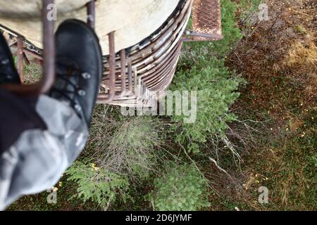 Blick von einer rostigen Leiter auf eine alte Betonsäule. Stockfoto