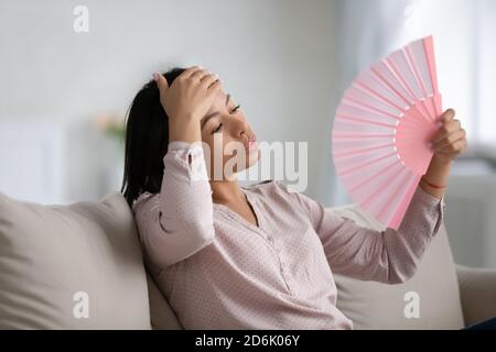 Überhitzte Biracial Frau verwenden Handventilator zu Hause Stockfoto