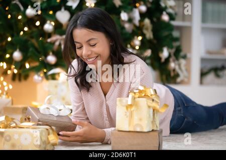 Lächelnde Biracial Frau Auspacken verpackt Weihnachtsgeschenk Stockfoto