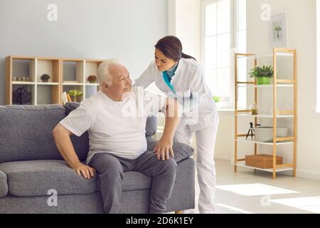 Krankenschwester hilft älteren Mann vom Sofa aufstehen Modernes Krankenhaus oder geriatrische Rehabilitationszentrum Stockfoto