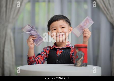 Asiatische chinesische Junge, Verwaltung der Finanzen, setzen Geld in Sparschwein Stockfoto