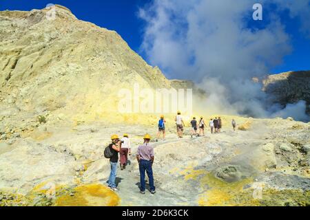 Touristen auf White Island, einem aktiven Vulkan vor der Küste Neuseelands, wandern in Richtung des dampfenden Kratersees Stockfoto