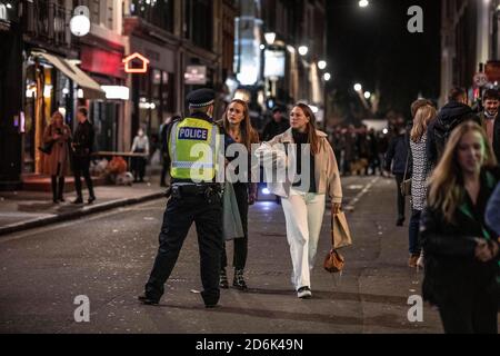 Ein paar junge Frauen werden von der Polizei abgewiesen, die auf der Old Compton Street patrouilliert, während das, was als die letzte Nacht der Freiheit als Stufe 2-Lockdown gilt, auf Versammlungen in Restaurants und Bars in Soho, London, Großbritannien erzwungen wird.Quelle: Jeff Gilbert/Alamy Live News Stockfoto