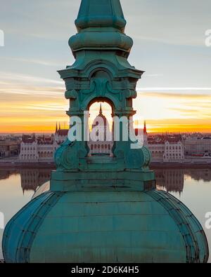 Einzigartiges Foto über das ungarische Parlamentsgebäude durch einen Glockenturm der Kirche. Tolle Morgenstimmung. Stockfoto