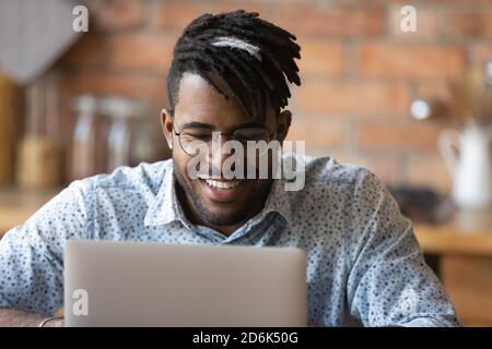 Lächelnder Biracial Mann in Brille arbeiten auf Laptop Stockfoto