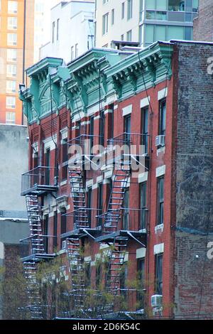 Typisches New yorker Stadtgebäude in Nachbarschaft mit rotem Backsteingebäude Schnee mit Feuerflucht Stockfoto