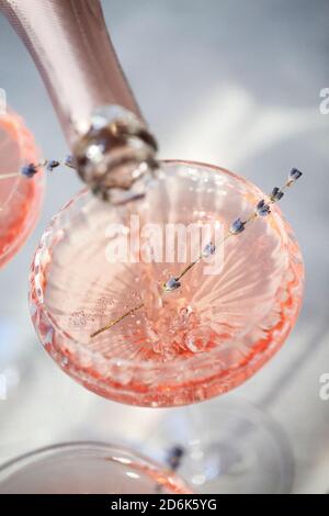 Von oben der anonymen Person Gießen Sekt in Glas Mit Blumen auf dem Tisch im Restaurant Stockfoto