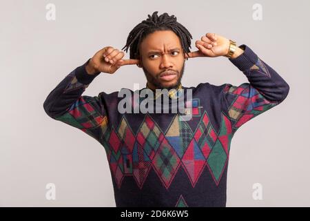 Ich will das nicht hören. Verärgert frustrierter afrikanischer Kerl mit Dreadlocks Ohren schließen mit Fingern, die Informationen ignorieren, müde von irritierender Lärm. Zoll Stockfoto