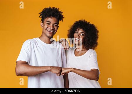 Bild eines glücklichen afroamerikanischen Paares, das lächelt und Faust gibt Bump isoliert über gelbe Wand Stockfoto