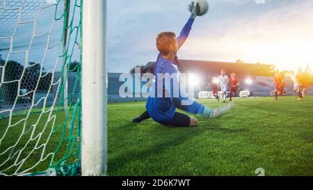 Auf Stadion Angreifer Kicks the Ball und Tore, Fußball Torwart versucht, Tore springt und fangen den Ball zu verteidigen. Aufnahme mit warmem Sonnenlicht Stockfoto