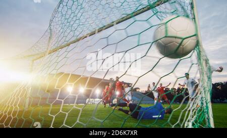 Auf Fußball-Meisterschaft Torwart versucht, Tore zu verteidigen, aber springt und scheitert, den Ball zu fangen. Aus dem Netz mit dem Ball in ihm geschossen. Stadion Stockfoto