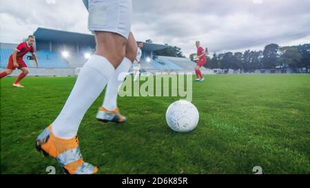 Low Angle Schuss eines professionellen Fußballspielers vor dem Kicken des Balls. Zwei Profifußballteams, die auf einem Stadion spielen. Stockfoto