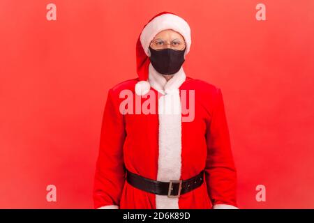 Porträt von älteren weihnachtsmann in Brillen Tragen Sie Schutzmaske ernsthaft Blick auf Kamera, Coronavirus und Winterferien. Studio-Zimmer im Innenbereich Stockfoto