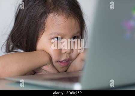 Absorbiertes junges Kind, das sich einen Film online auf einem Laptop-Computer zu Hause aus der Nähe ansieht. Stockfoto