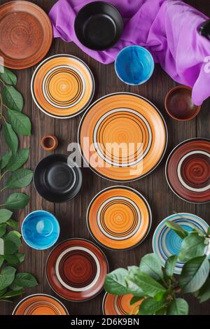 Farbige leere Teller und Schüsseln auf einem Holzhintergrund. Das Konzept der alten Rezepte und traditionelle Küche. Draufsicht Stockfoto