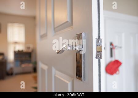 Flacher Fokus eines Innentürgriffs an einer Brandschutztür. Der Eingang führt zu einem Wohnzimmer eines Privathauses. Stockfoto