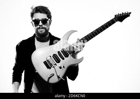 Ein Mann mit einer Gitarre Emotionen Musik Spiel Performance Leder Jacke Sonnenbrille Licht Hintergrund Stockfoto