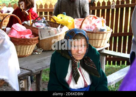 Ältere Frau in Oltenia, Rumänien. Zusammenkunft mit Almosenkörben im Hof einer christlich-orthodoxen Kirche. Stockfoto