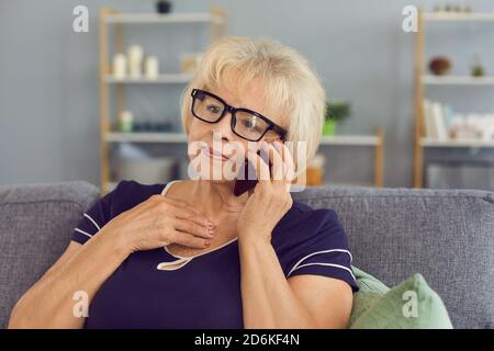 Reife Frau mit Brille hat ein Telefongespräch mit ihrem alten Freund mit einem Handy. Stockfoto