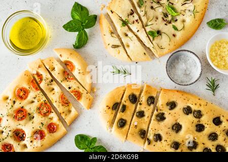Italienisches Focaccia-Brot mit verschiedenen Gemüsefüllungen. Frisch gebackene Focaccia mit Tomaten, Oliven, Knoblauch und Kräutern, Draufsicht. Stockfoto