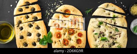 Italienisches Focaccia-Brot mit verschiedenen Füllungen auf schwarzem Hintergrund. Frisch gebackene Focaccia mit Tomaten, Oliven, Knoblauch und Kräutern, Draufsicht, Banner. Stockfoto