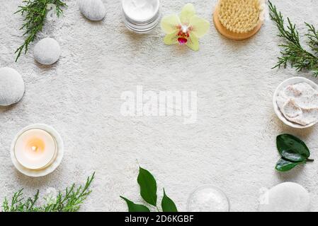 Natürliche Hautpflege und Spa auf weißen weichen Handtuch Hintergrund mit Naturkosmetik, Blume, grüne Blätter, Kerze und zen wie Steine. Entspannen c Stockfoto
