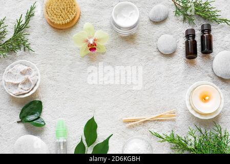 Natürliche Hautpflege und Spa auf weißen weichen Handtuch Hintergrund mit Naturkosmetik, Blume, grüne Blätter, Kerze und zen wie Steine. Entspannen c Stockfoto
