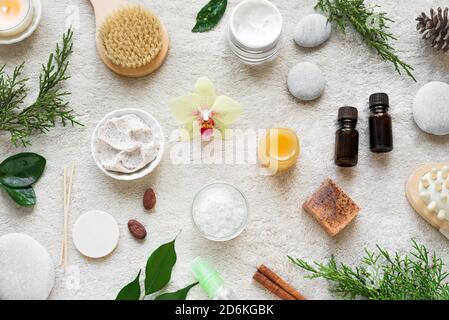 Natürliche Hautpflege und Spa auf weißen weichen Handtuch Hintergrund mit Naturkosmetik, Blume, grüne Blätter, Kerze und zen wie Steine. Entspannen c Stockfoto