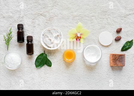 Natürliche Hautpflege und Spa auf weißen weichen Handtuch Hintergrund mit Naturkosmetik, Blume, grüne Blätter, Kerze und zen wie Steine. Entspannen c Stockfoto