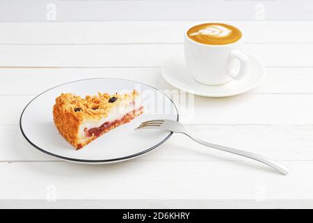 Tasse Kaffee und Stück hausgemachten Kuchen mit Hütte Käse-Souffle und Pflaume mit Mandeln und Heidelbeeren auf Weißer Holztisch Stockfoto