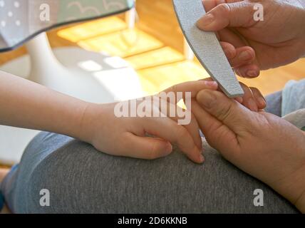 Hände einer Frau, die die Zehennägel eines Kindes einfeilen Stockfoto