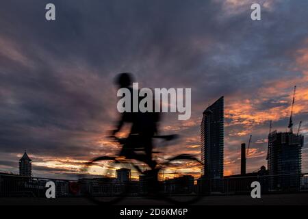 Ein Radfahrer mit Silhouette vor dem Hintergrund des Lots Road Kraftwerks, Chelsea Harbour und Stockfoto